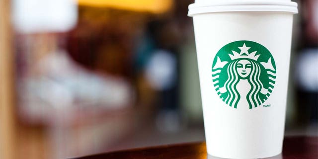 "Halifax, Nova Escócia, Anada - 18 de setembro de 2011: Grande Starbucks vai para um copo sentado em uma mesa.  A Starbucks é uma franquia internacional de cafeterias extremamente popular, com mais de 15.000 locais em 50 países"
