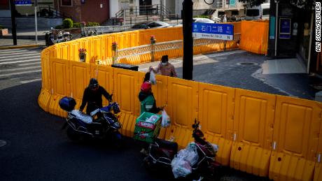 Um entregador passa comida para uma mulher sobre as barreiras de uma área fechada em Xangai em 23 de março de 2022. 