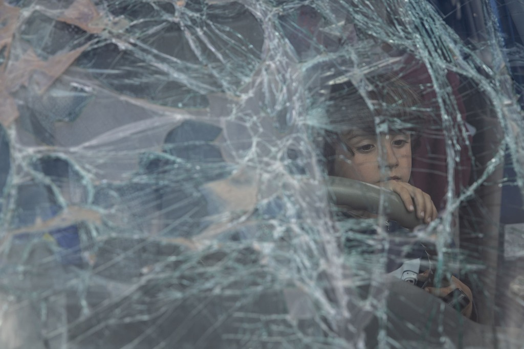 Um menino de Mariupol olha pelo para-brisa quebrado do carro de sua família