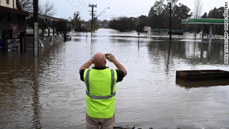 Um cidadão local tira uma foto de uma estrada inundada em Camden, no sudoeste de Sydney, domingo, 3 de julho de 2022.