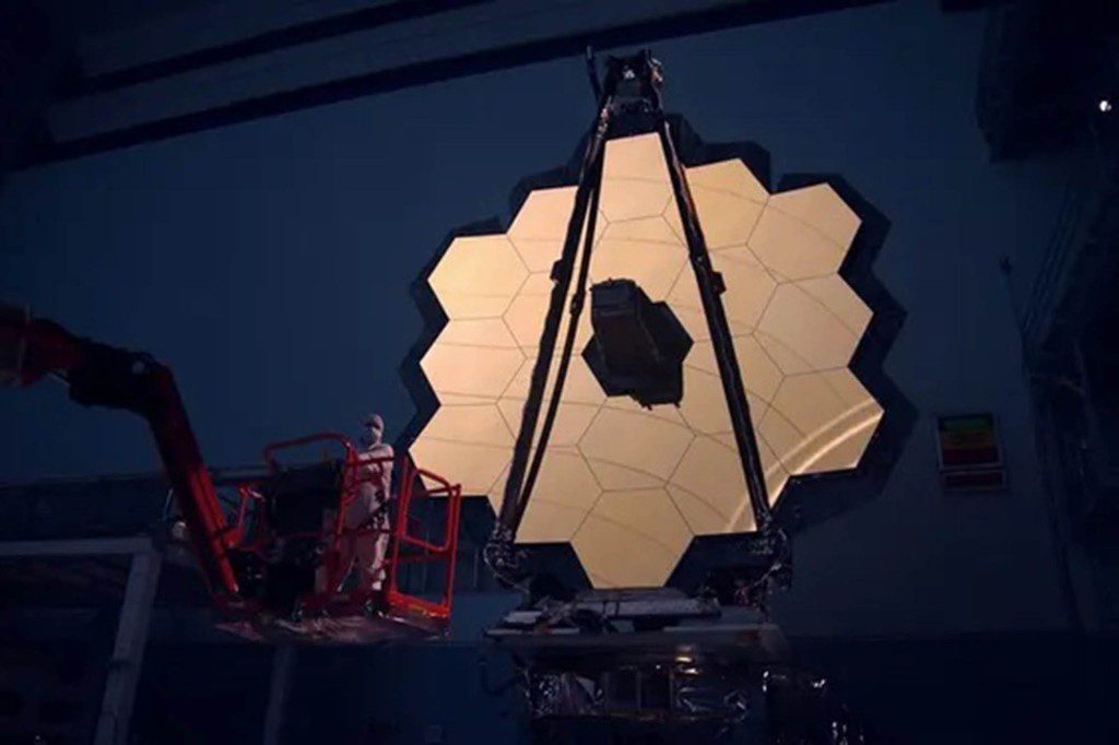 O espelho principal do Telescópio Espacial James Webb é iluminado na câmara escura
