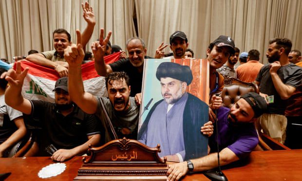 Apoiadores carregam uma foto do clérigo xiita iraquiano Muqtada al-Sadr dentro do prédio do parlamento em Bagdá.