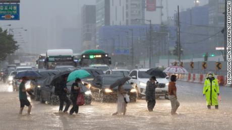 Pedestres atravessam uma estrada inundada em Gimpo, Seul, em 9 de agosto.