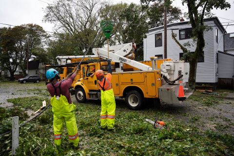 Trabalhadores levantam fios caídos para permitir que máquinas alcancem árvores caídas em Halifax no sábado.