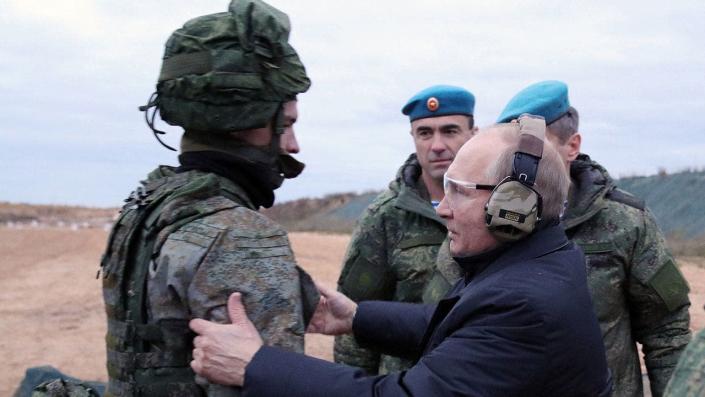 Putin usa uma orelha e um olho protetores enquanto fala com o soldado
