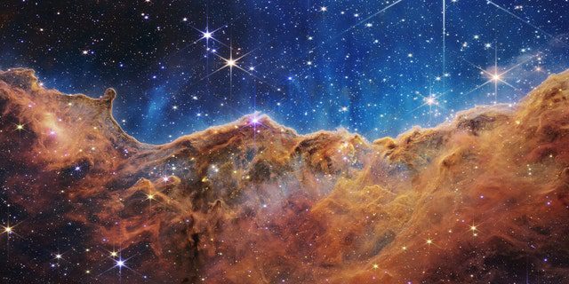 O que se parece muito com montanhas rochosas em uma noite de luar é, na verdade, a borda da jovem região de formação de estrelas NGC 3324 na Nebulosa de Carina.  Obtida em luz infravermelha pela Near Infrared Camera (NIRCam) no Telescópio Espacial James Webb da NASA, esta imagem revela regiões anteriormente obscurecidas de nascimento de estrelas.
